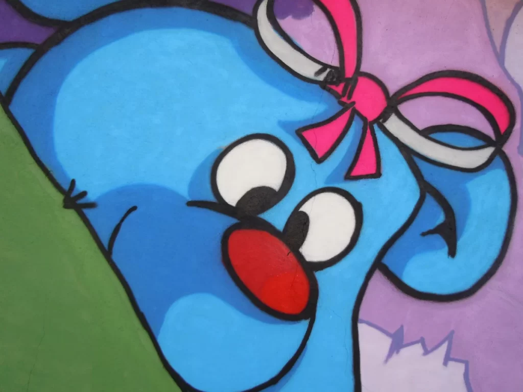 Gros plan sur l'ours en peluche bleu avec un ruban rose fluo sur la tête.