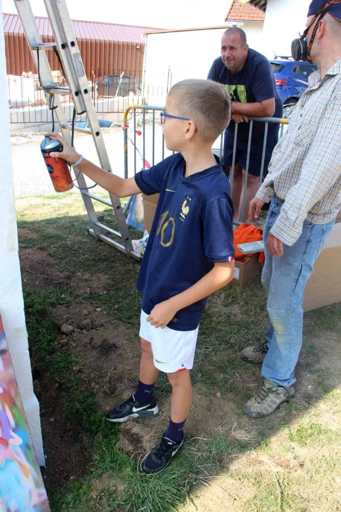 photo d'un enfant en train de peindre une fresque street art de Dragon Ball.