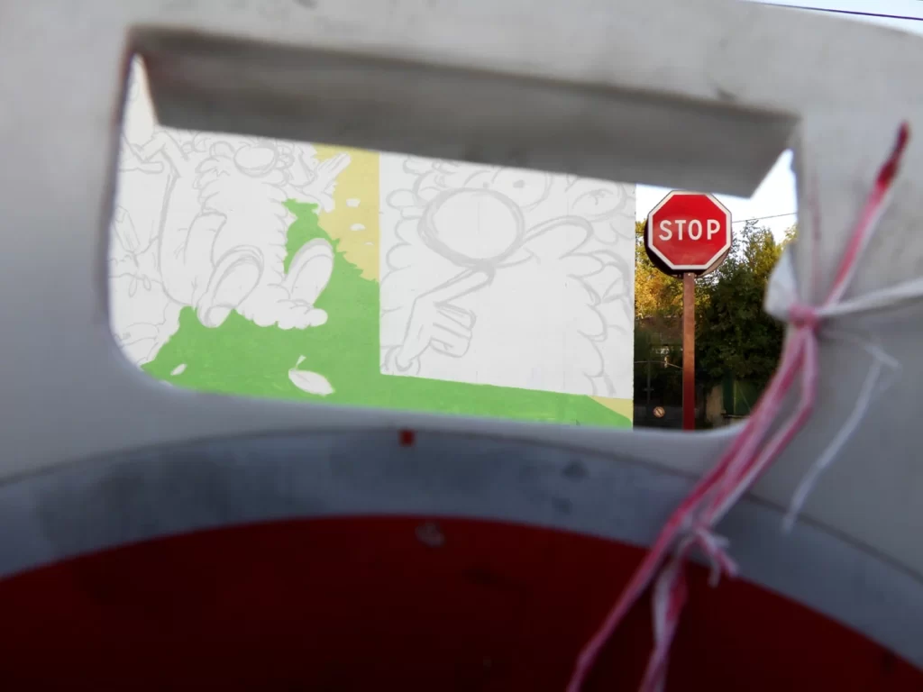 Photo montrant une partie de la fresque de Léonard le génie à Nontron avec à coté un panneau stop.